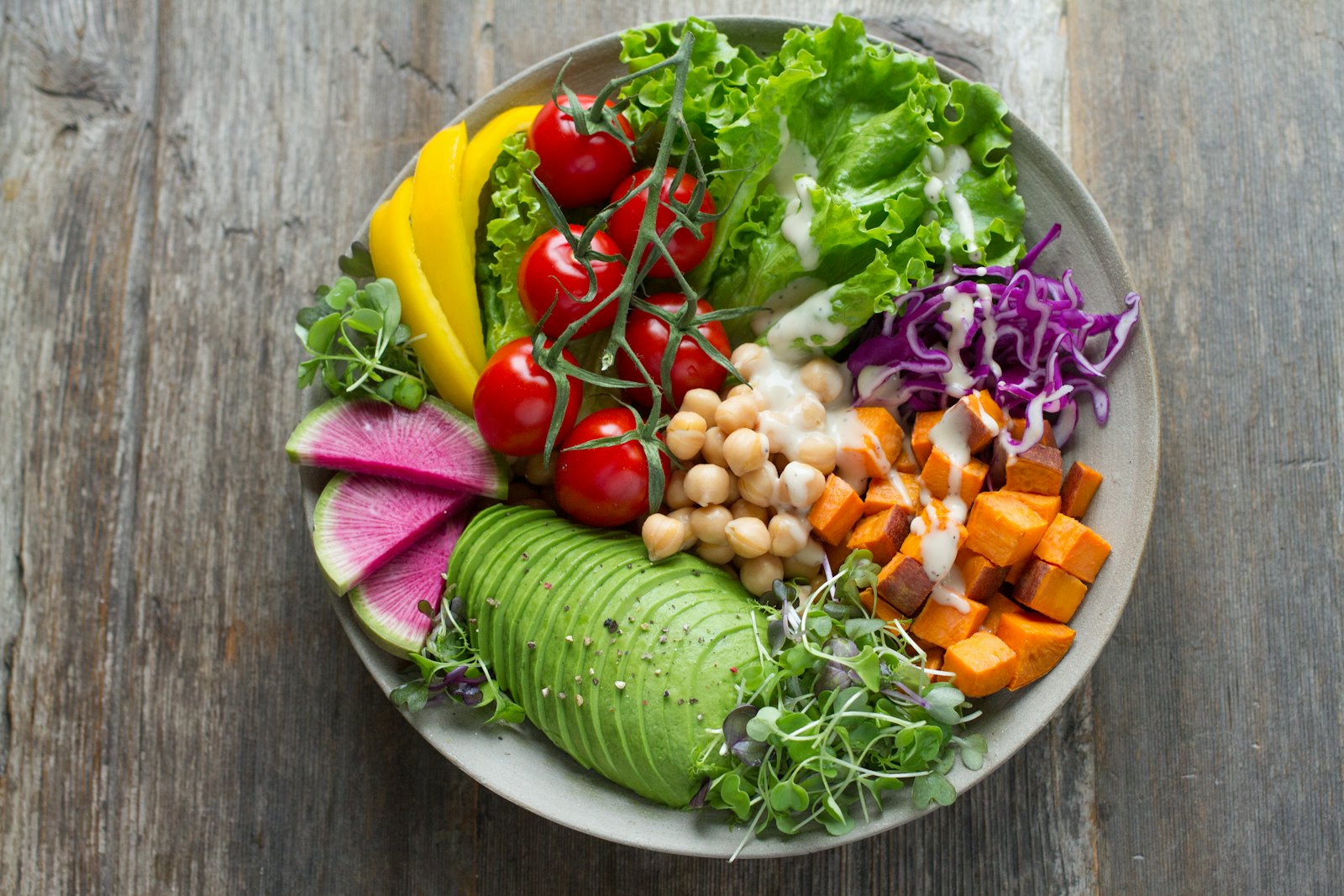 A grain bowl with chickpeas, avocado, tomato, and sweet potato