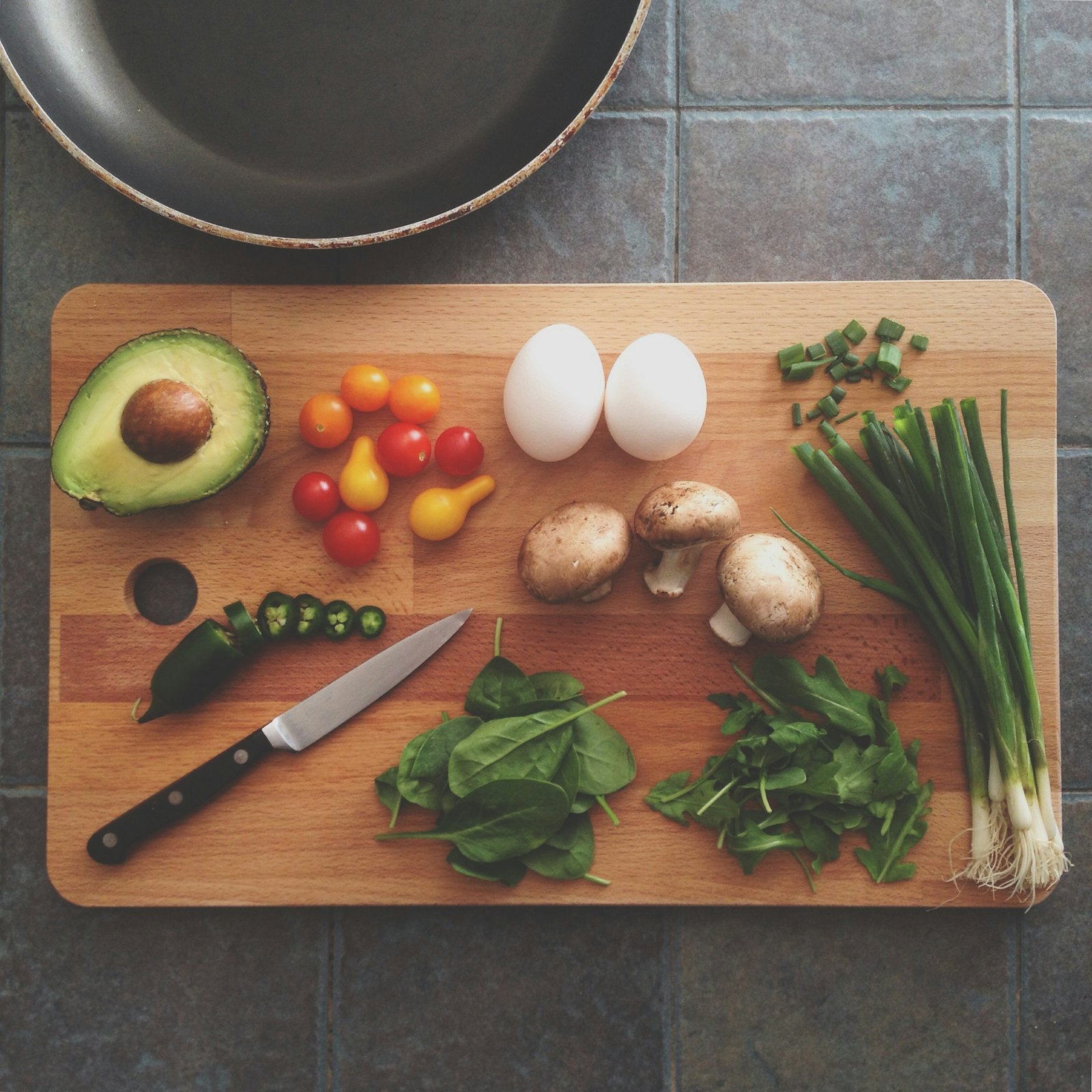 Fresh vegetables, eggs, and herbs laid out on a wooden cutting board