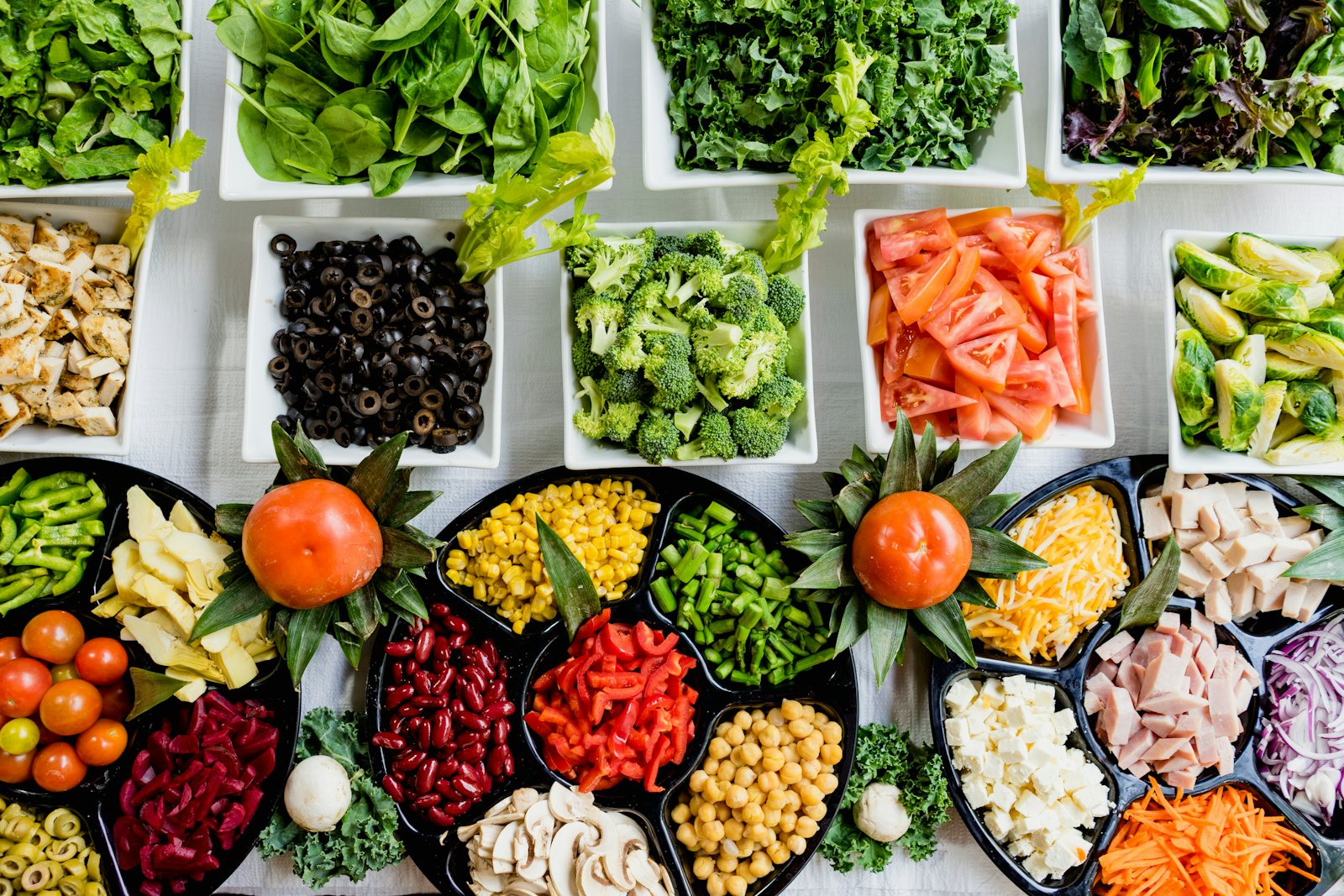 Small dishes of vegetables, beans, and greens portioned out on a table
